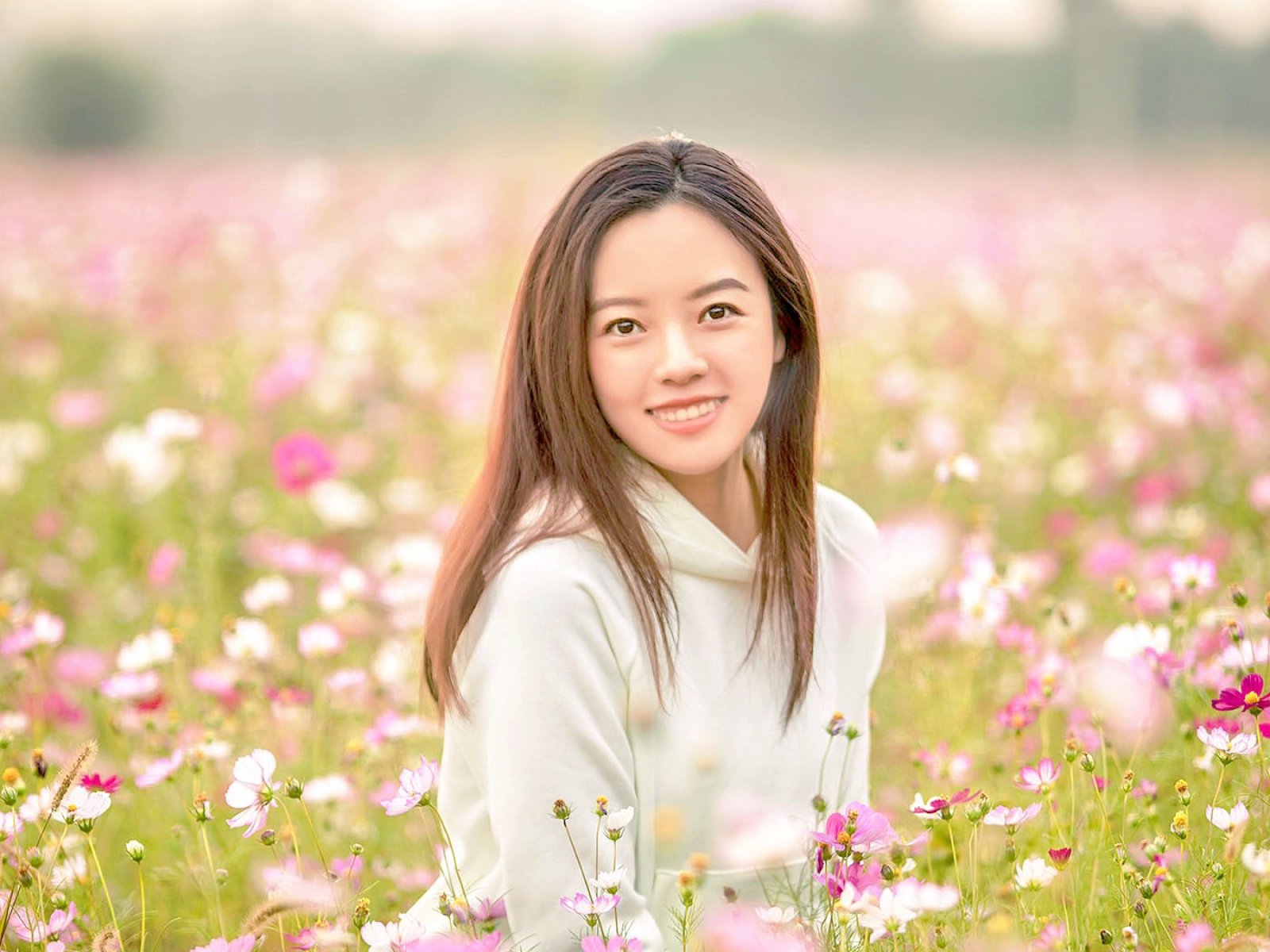 happy young woman enjoying summer in yellow field at sunset