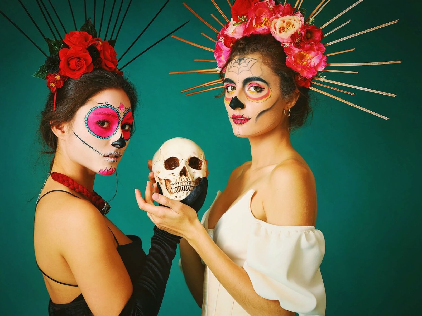 Women with painted faces and skull on dark green background. Celebration of Mexico's Day of the Dead (El Dia de Muertos)