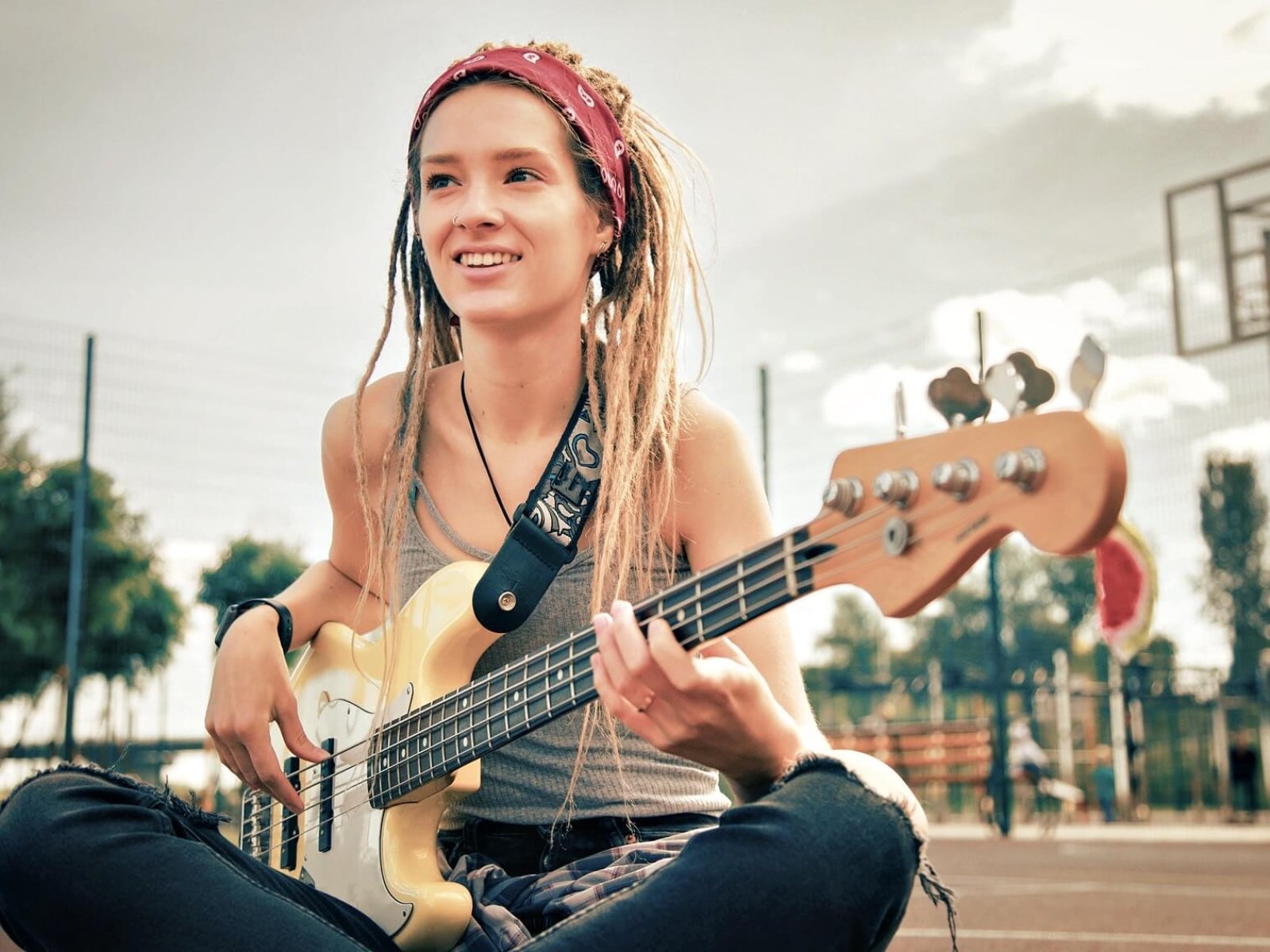 Happy lady smiling and looking into the distance while playing the guitar